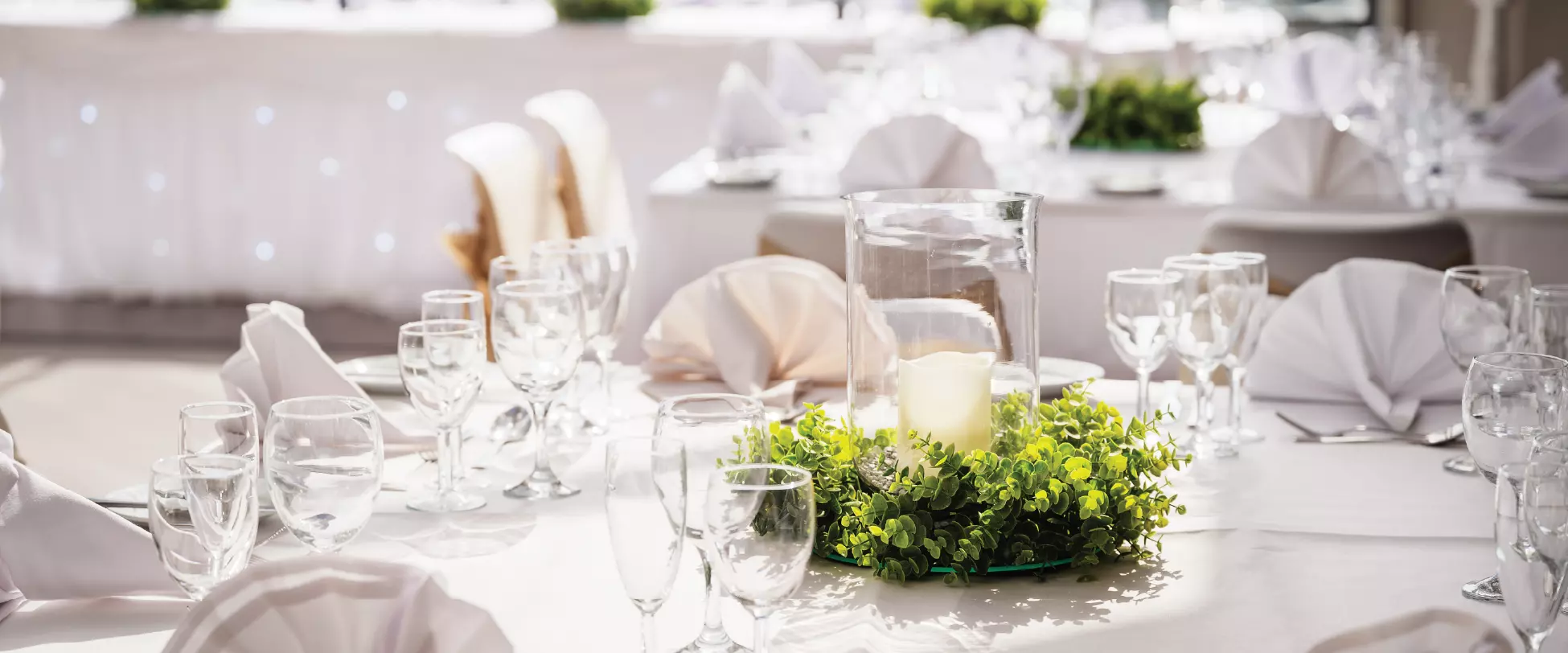 A table set up for a wedding with white linens and glassware..